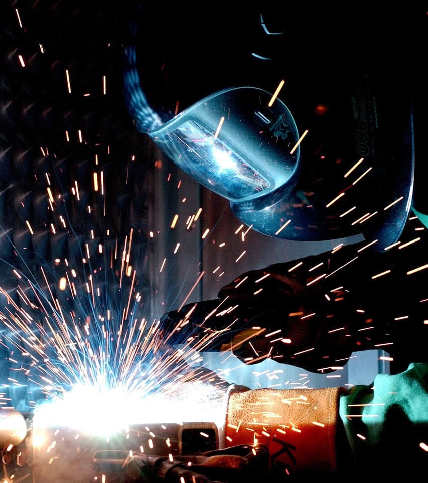 A welder that is welding something with sparks flying.